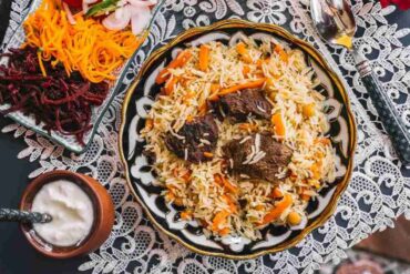 Hygienically prepared Kabsa with tender meat, carrots, and chickpeas, served with fresh vegetables and yogurt, emphasizing food safety.